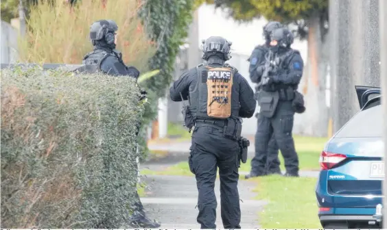  ?? Photo / Mark Mitchell ?? Police armed offenders squad members positioned on Bledisloe St, Levin, as they negotiate with a man who had barricaded himself in a house on the street, forcing the evacuation of a number of nearby residents from their homes.