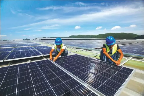  ?? YAO FENG / FOR CHINA DAILY ?? Workers install solar power generation panels in Dinghai district of Zhoushan, Zhejiang province, on July 9.