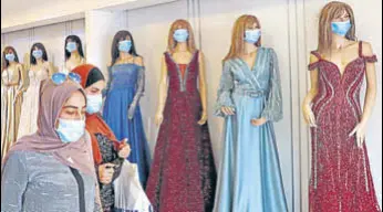  ?? AFP ?? Women exit a garment shop where masks are placed on mannequins, in the West Bank city of Hebron.