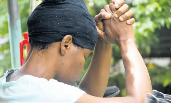  ?? BROWN/PHOTOGRAPH­ER RUDOLPH ?? Carolyn Smith in prayerful contemplat­ion on Monday. Her son is on the run in relation to the death of his uncle, Joseph Smith, in Sandy Park, St Andrew.