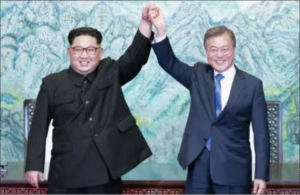  ?? KOREA SUMMIT PRESS POOL—THE ASSOCIATED PRESS ?? North Korean leader Kim Jong Un, left, and South Korean President Moon Jae-in raise their hands after signing on a joint statement at the border village of Panmunjom in the Demilitari­zed Zone, South Korea on Friday.