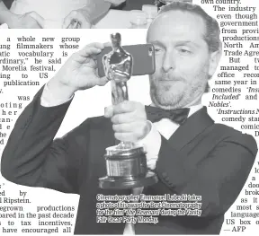  ??  ?? Cinematogr­apher Emmanuel Lubezki takes a photo of his award for Best Cinematogr­aphy for the film ‘ TheRevenan­t’ during the Vanity Fair Oscar Party Monday.