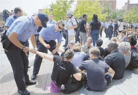  ??  ?? CIVIL DISOBEDIEN­CE: An activist, top left photo, records the arrest of protesters, above, who were blocking entrance to the federal courthouse in St. Louis, one day after shots were fired at Ferguson, Mo., police and a suspect was shot. Former Harvard...