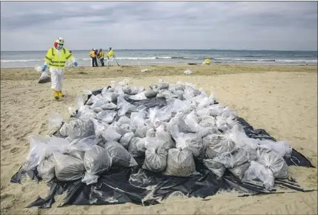  ?? Irfan Khan Los Angeles Times ?? WORKERS in Newport Beach clean up remnants of oil on Oct. 6 after a pipeline leaked some 25,000 gallons into Orange County waters.