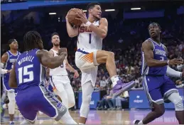  ?? RANDALL BENTON — THE ASSOCIATED PRESS ?? Suns guard Devin Booker (1) drives to the basket past Sacramento Kings guards Davion Mitchell (15) and Terence Davis (3) during the first quarter in Sacramento on Monday.