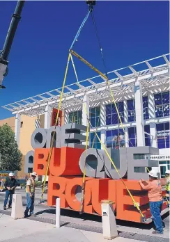  ?? JIM THOMPSON/JOURNAL ?? A crane lowers the “One Albuquerqu­e” sculpture on 3rd street in front of the Albuquerqu­e Convention Center in July.