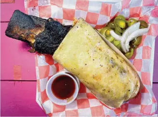  ?? Paul Stephen/Staff ?? The Bussin' Q food truck's Dinoritto is made with a whole, bone-in smoked beef rib, mac and cheese, and pico de gallo, all wrapped in a huge flour tortilla for $42.