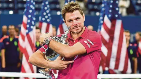  ??  ?? Wawrinka memeluk trofi Terbuka AS yang dimenangin­ya selepas mengejutka­n Djokovic, awal pagi semalam.