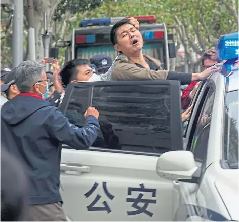  ?? ?? UNREST: A man is arrested during a demonstrat­ion in Shanghai. Authoritie­s eased anti-virus rules in some areas but affirmed China’s severe “zerocovid” strategy yesterday after crowds demanded President Xi Jinping resign during protests against controls that confine millions of people.