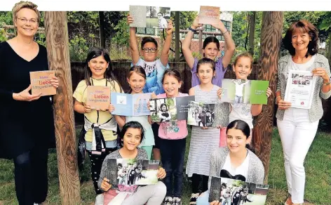  ?? FOTO: KEMPKEN ?? Stolz halten Angelika Tenberg (v.l.), die neun Teilnehmer des Projekts sowie Claudia Kaßelmann von der Bürgerstif­tung Kreaktiv das Buch in die Kamera.