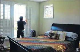  ??  ?? Andrew Sakallaris, 68, adjusts the shutters in the first-floor master bedroom at his home in the Railroad Cottages community in Falls Church, Virginia.