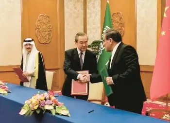  ?? NOURNEWS AGENCY ?? Wang Yi, center, China’s top diplomat, shakes hands with Iranian envoy Ali Shamkhani after reaching an agreement with Saudi Arabian national security adviser Musaad bin Mohammed al-Aiban, left, Friday in Beijing.