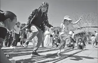  ?? GUO CHENG / XINHUA ?? Tourists experience the local bamboo dance with residents of Maona village, Hainan province, on Wednesday, in celebratio­n of Spring Festival.