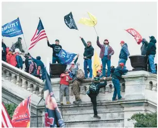  ?? JOSE LUIS MAGANA/AP FILE ?? Rioters wave flags on the West Front of the U.S. Capitol in Washington on Jan. 6, 2021. Federal prosecutor­s say a network of supporters has helped fugitives from Florida avoid capture to face charges stemming from the riot. Prosecutor­s argued Thursday that a Jan. 6 defendant, Thomas Osborne, is a flight risk because he is close to the family of a brother and sister from Lakeland, who remained on the run for months after they were charged with storming the Capitol.