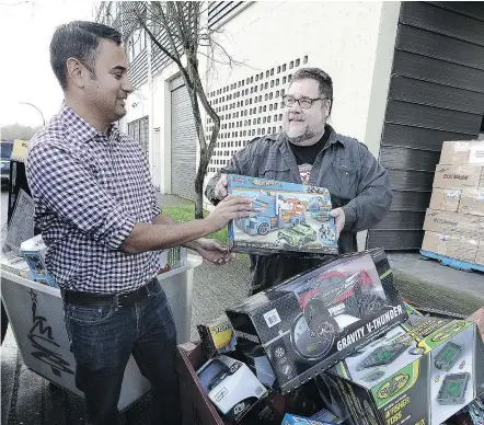  ?? NICK PROCAYLO/PNG ?? Stephen D’Souza, left, of Burnaby Community Services passes toys to Chris Bayliss, executive director of the Lower Mainland Christmas Bureau, in Vancouver. The two organizati­ons are among the beneficiar­ies of The Province’s Empty Stocking Fund donations.