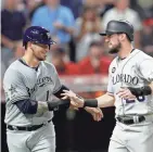  ?? AP ?? Yasmani Grandal (left) and David Dahl greet each other after scoring for the NL in the eighth inning.