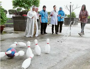  ??  ?? Stroke patient Puan Su yeong (right), 23, doing a hand-strengthen­ing and social exercise at the uMMC Rehabilita­tion Medicine department’s Therapeuti­c Sensory Stimulatio­n Garden as Prof Zaliha (left) and some of the department’s physiother­apists watch....