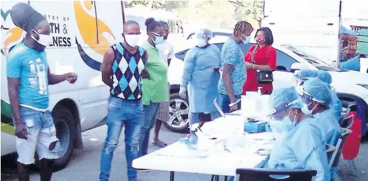  ?? PHOTO BY RUDDY MATHISON ?? Health workers in personal protective gear prepare to administer COVID tests to residents of Tawes Meadows who came out for testing on Saturday.