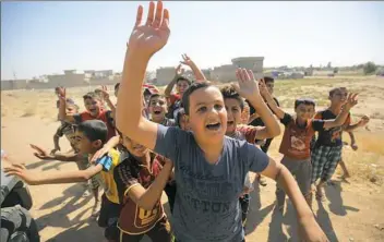  ?? Ahmad Al-Rubaye/AFP/Getty Images ?? Iraqi children wave to Iraqi forces as they arrive in the first neighborho­od on the southern outskirts of Kirkuk on Monday.