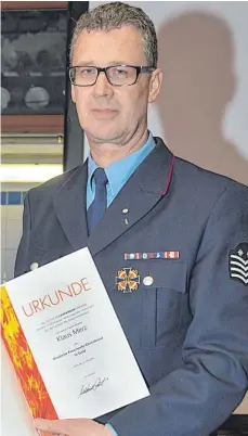  ?? FOTO: KLAUS WEISS ?? In der blauen Feuerwehru­niform, so kennt man ihn: Klaus Merz mit der Urkunde des Deutschen Feuerwehrv­erbands. Das Deutsche Feuerwehr-Ehrenkreuz in Gold ist rechts daneben an seine Jacke geheftet.