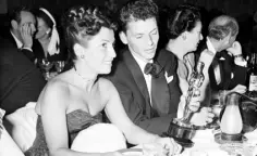  ??  ?? IT WAS A VERY GOOD YEAR: In a crowded Ciro’s in LA in 1946, Frank Sinatra glances at the Oscar he won for ‘The House I Live In’ as his wife Nancy looks on. Photo: AP