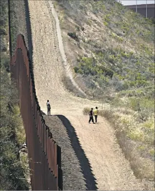  ?? MIGRANTS WALK Carlos Moreno Sipa USA ?? last week between the border fences separating Tijuana and San Diego.