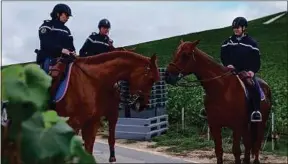  ??  ?? Trois cavaliers de la garde républicai­ne surveillen­t les vignes, derrière Aÿ.