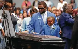  ??  ?? Terrance Mitchell Sr. and his 10-year-old son, Adrian, touch the casket of Terrance “T.J.” Mitchell on Saturday at Christ United Methodist Church.