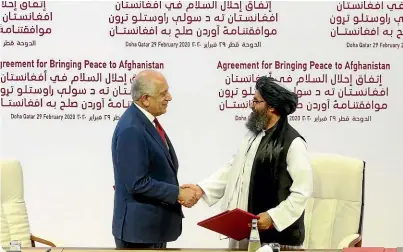  ?? AP ?? US envoy Zalmay Khalilzad, left, and Mullah Abdul Ghani Baradar, the Taliban’s top political leader, shake hands after signing the Afghanista­n peace agreement in Doha, Qatar.