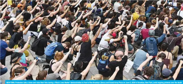  ??  ?? NEW YORK: Protesters take a knee and raise their fists during a ‘Black Lives Matter’ demonstrat­ion in front of the Brooklyn Library and Grand Army Plaza on June 5, 2020 in Brooklyn, New York, amid ongoing protests over the death in police custody of George Floyd. — AFP