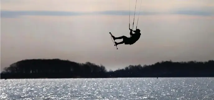  ?? NANCY LANE PHOTOS / HERALD STAFF ?? CATCHING A BREAK: A kite surfer catches some air near thethe city’s L Street bathhouse on Sunday when temperatur­es rose to make it a nice day.