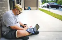  ?? AP PHOTO/BRYAN WOOLSTON ?? Barlow Mitchell sits outside the Lee County Public Library while using the public Wi-Fi, in Beattyvill­e, Ky., on July 29.