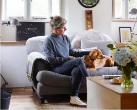  ??  ?? THIS PAGE, FROM TOP Sylvie and the family’s rescue dog, Otis, relax in the comfy living room; the porch area was added, using salvaged timbers, while the exterior was hung with slate tiles; in the kitchen, a wooden crate is mounted on the wall as an