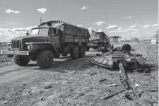  ?? Bernat Armangue /Associated Press ?? Ukrainian army vehicles drive past the remains of a Russian tank Friday in north Kharkiv, Ukraine.