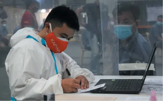  ?? Photo by Jean Nicole Cortes ?? NO LET UP. A nurse interviews a returning Baguio resident at the St. Vincent gym. Health officials call on the public to comply with the triage rules for proper documentat­ion on ingress and egress of people in Baguio.