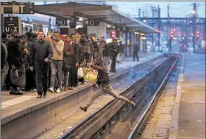  ?? AP/FRANCOIS MORI ?? A passenger crosses railroad tracks at rush hour at Gare de Lyon train station in Paris as railroad workers stage a mass strike on Tuesday. French unions plan strikes two days every week through June to protest government plans to eliminate some rail...