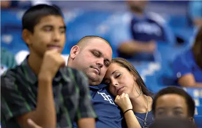  ?? AP Photo/Phelan M. Ebenhack, File ?? ■ In this Sept. 21, 2013, file photo, two Tampa Bay Rays fans sleep in the stands during the 16th inning of a baseball game against the Baltimore Orioles in St. Petersburg, Fla. Major League Baseball will start each extra inning this season by putting a runner on second base. MLB is experiment­ing with the rule this year in part to prevent marathon games from causing long-term damage to pitching staffs in a pandemic-shortened season.