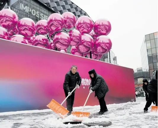  ?? AP ?? Workers sweep snow into a manhole near a decoration setup ahead of the Christmas festival at a mall in Beijing, on December 14, 2023. China’s exports grew slightly for a second consecutiv­e month in December even as deflationa­ry pressures continue, according to official data released Friday, January 12, 2024, underscori­ng an uneven recovery in 2023.