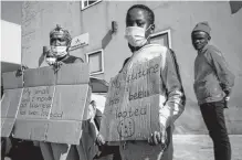  ?? REUTERS ?? People stand with placards as South African President Cyril Ramaphosa visits a shopping centre which was damaged after several days of looting following the imprisonme­nt of former South Africa President Jacob Zuma in Durban, South Africa.