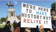  ?? STEVE HELBER/ASSOCIATED PRESS ?? A protester holds up a sign in front of a statue of Confederat­e Gen. Robert E. Lee in Richmond, Va., in September 2017. A woman was run down and killed at the rally.