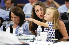  ?? MANUEL BALCE CENETA / ASSOCIATED PRESS
Washington Post ?? U.S. Rep. Jaime Herrera Beutler (center), R-Wash., holds her daughter, Abigail, as she sits next to U.S. Rep. Martha Roby, R-Ala., during a hearing Wednesday on congressio­nal spending bills. A Republican fiscal plan proposes deep cuts to safety net...