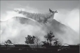  ?? ASSOCIATED PRESS ?? AN AIR TANKER DROPS RETARDANT AS THE MARIA FIRE approaches Santa Paula, Calif., on Friday. According to Ventura County Fire Department, the blaze has scorched more than 8,000 acres and destroyed at least two structures.