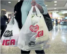  ?? THE CANADIAN PRESS FILES ?? A woman leaves a grocery store with plastic shopping bags. Victoria is the latest Canadian city to move ahead with a ban on single-use plastic bags.