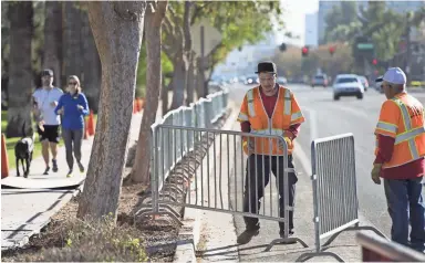  ?? DAVID WALLACE/THE REPUBLIC ?? Michael Garcia (center) and Albert Hernandez, both of Trafficade Service Inc., place barricades along Central Avenue on Thursday in preparatio­n for Saturday’s Fiesta Bowl Parade.