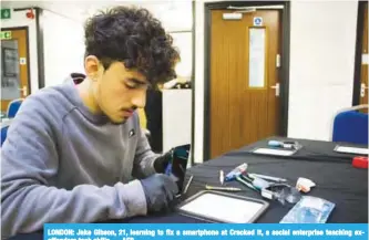  ??  ?? LONDON: Jake Gibson, 21, learning to fix a smartphone at Cracked It, a social enterprise teaching exoffender­s tech skills. — AFP