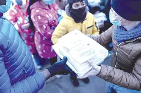  ??  ?? A volunteer of Madrina Foundation hands out food packages during a food and goods distributi­on.
