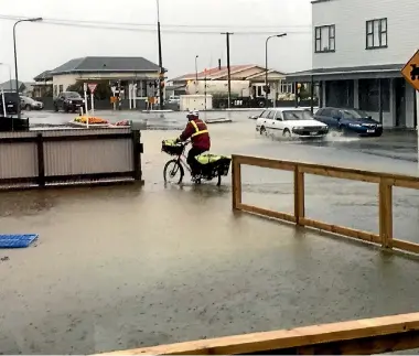 ??  ?? A postie braves flooding in Nelson St, Greymouth, after torrential rain on Thursday.