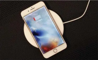  ?? PHOTOS BY MARK LENNIHAN — THE ASSOCIATED PRESS ?? The iPhone 8 Plus rests on a wireless charger.