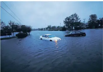  ?? FOTO: REUTERS ?? In der Stadt Wilmington (North Carolina) stehen verlassene Autos auf einer überflutet­en Kreuzung.
