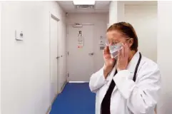 ??  ?? Nurse practition­er Patricia Smith puts on a mask before seeing a patient on Monday. Smith is motivated to make a difference to her patients, especially those in the trucking industry, where long hours, sedentary lifestyle and rigors of the job can lead...